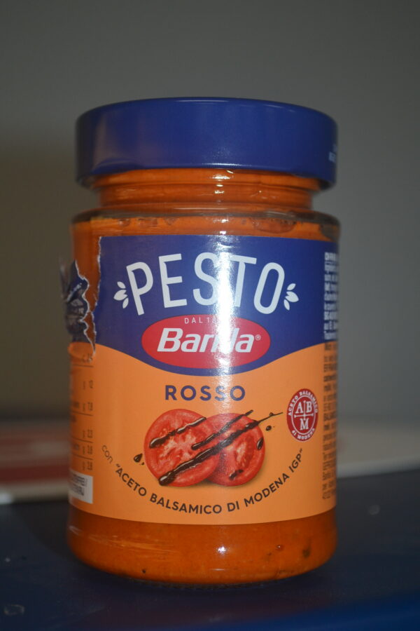 Barilla Pesto Rosso jar showcasing rich, deep red sun-dried tomato sauce with visible herbs, representing authentic Italian culinary excellence